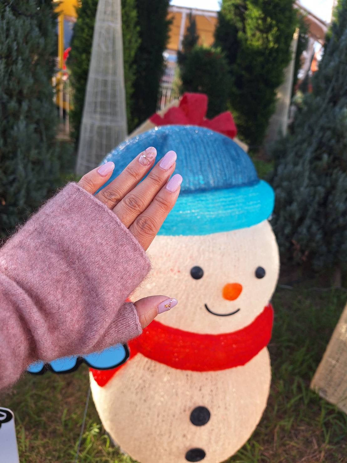 a beautiful manicured hand wearing New Zealand wristwarmers in front of a Japan snowman