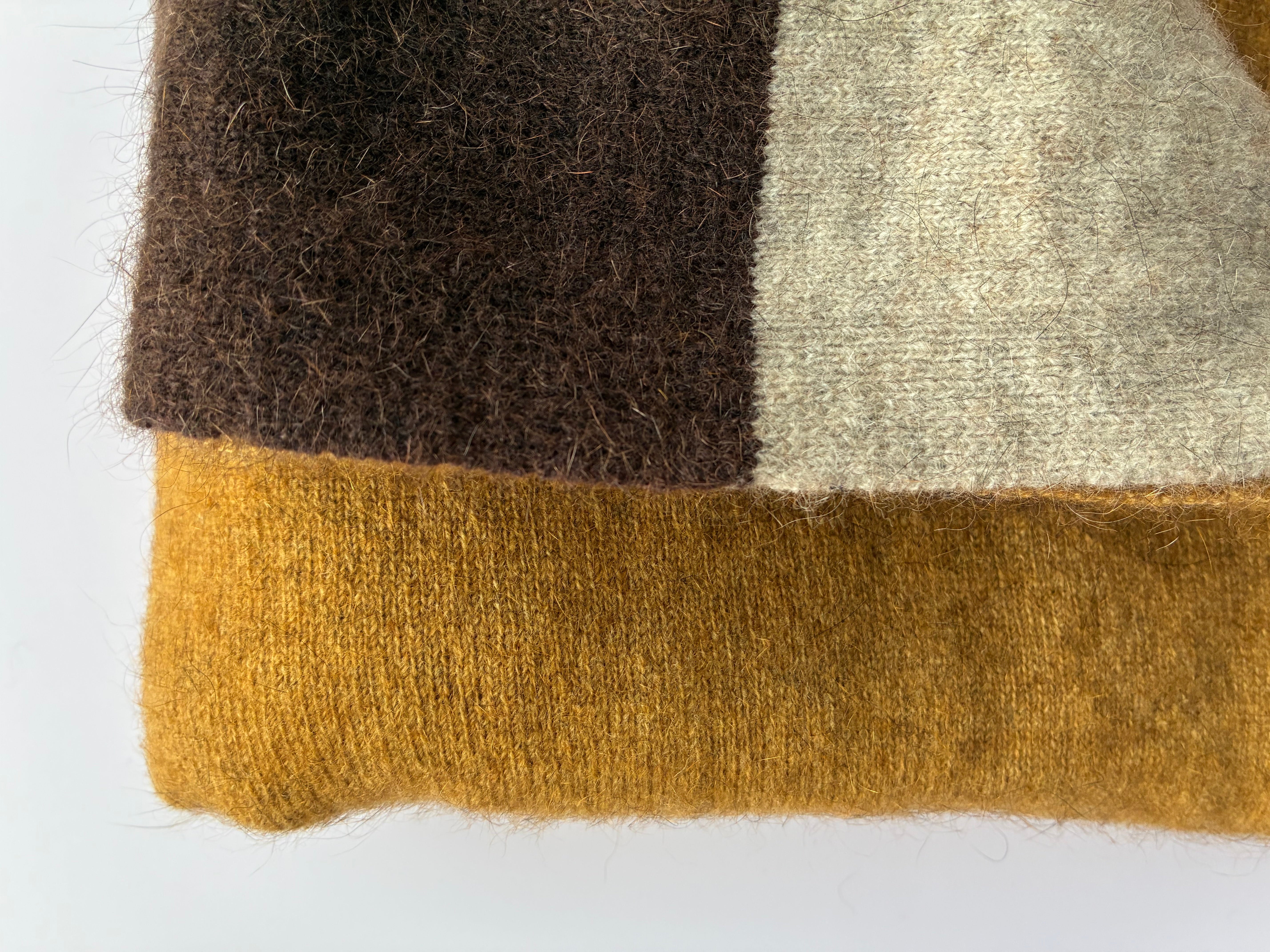 Close-up of a textured fabric with cocoa brown, natural beige, and marigold colors on a white background