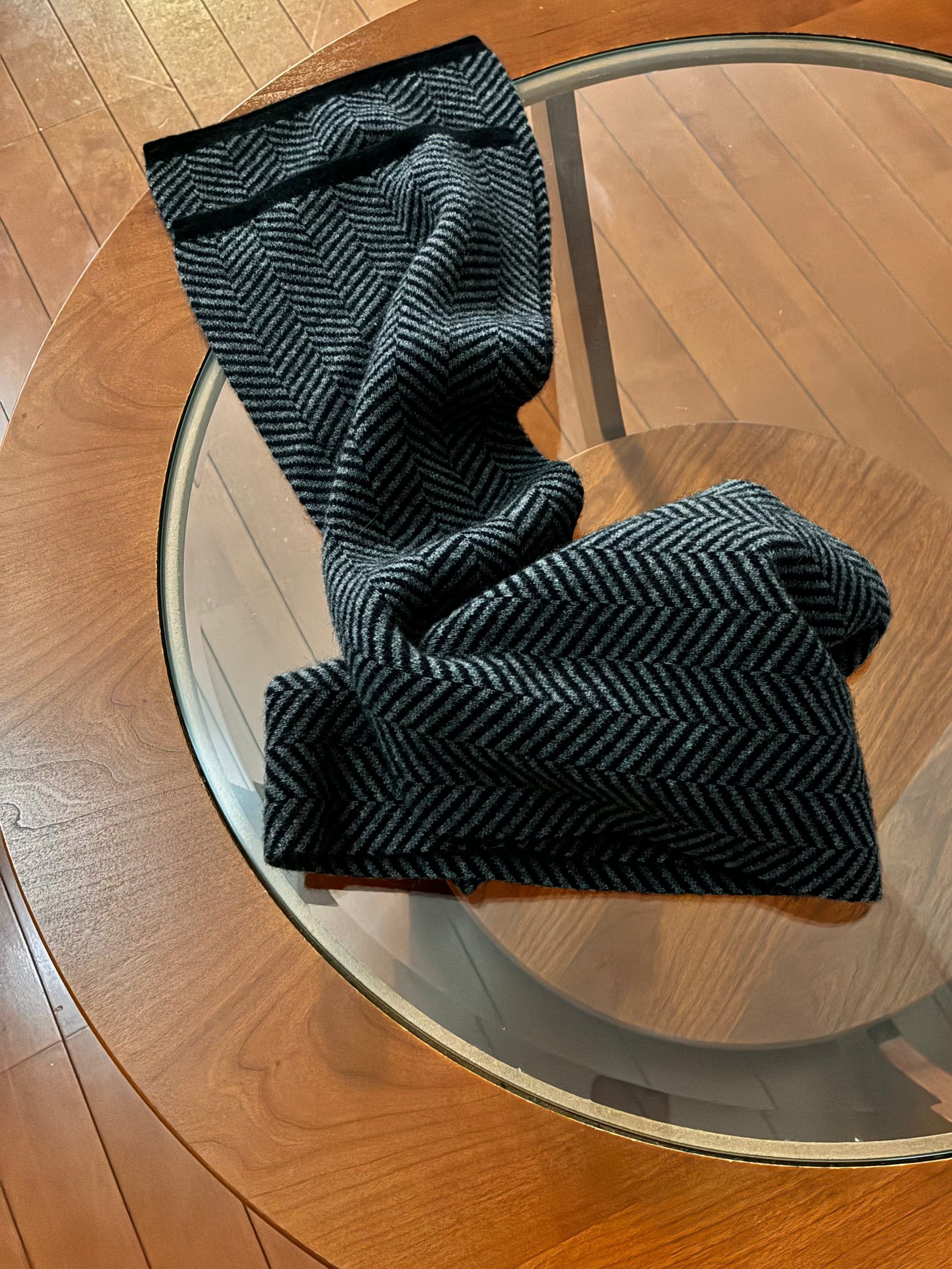 Black textured scarf on a round wooden mid century modern table with glass top
